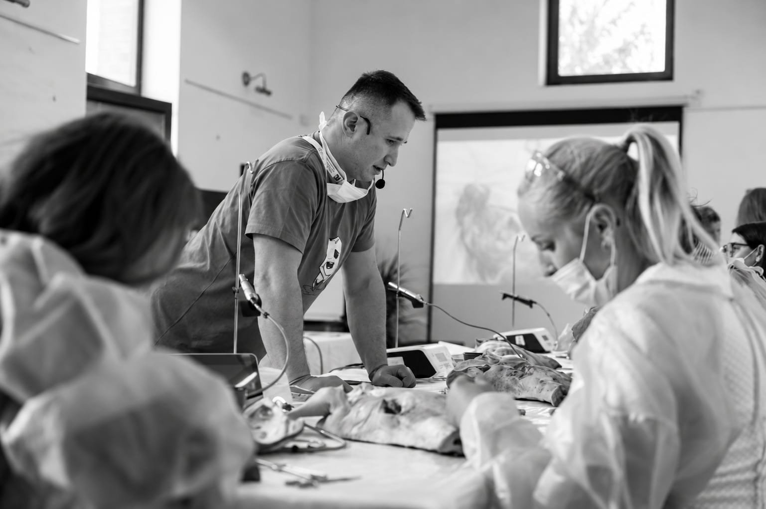 Černobílý snímek instruktora, který vede účastnici při praktickém výkonu